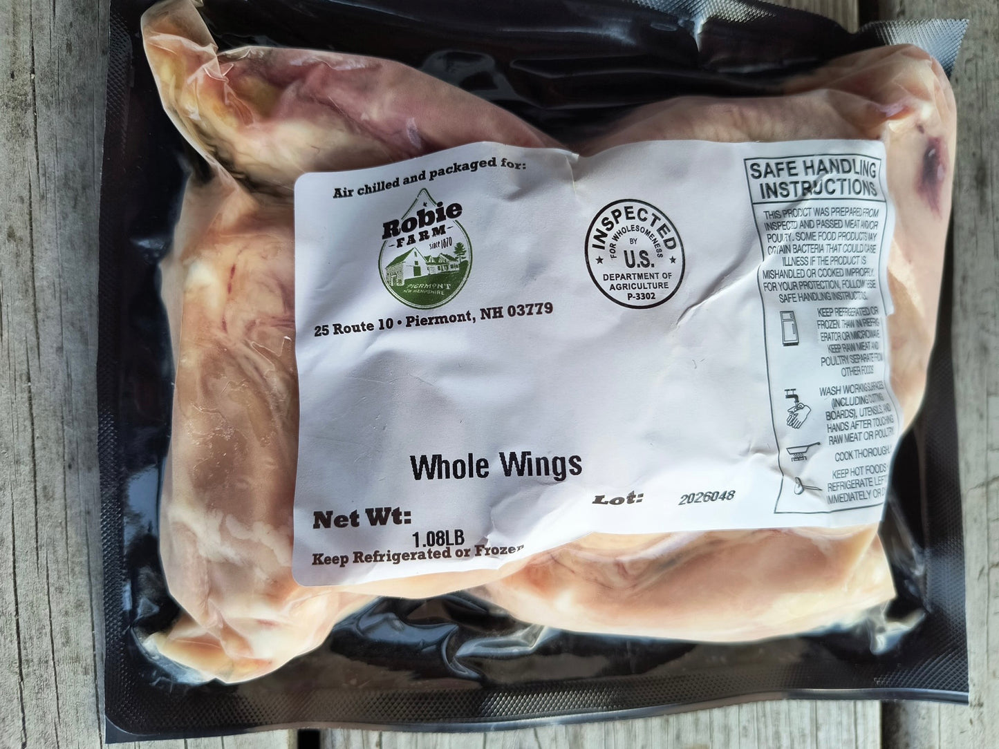 Packaged whole chicken wings with a Robie Farm label on a wooden surface