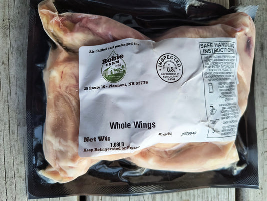 Packaged whole chicken wings with a Robie Farm label on a wooden surface