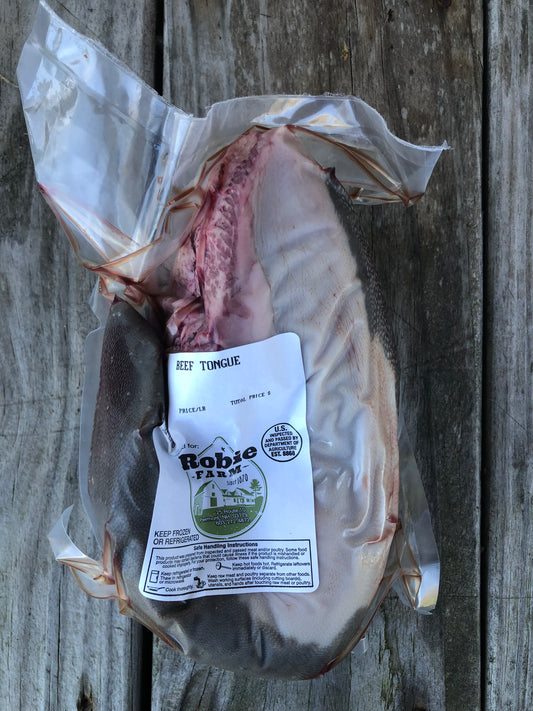 A vacuum-sealed Robie Farm beef tongue package lying on weathered wooden planks.