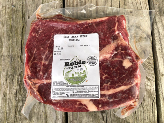 Package of a boneless Robie farm beef chuck steak resting on a wooden board