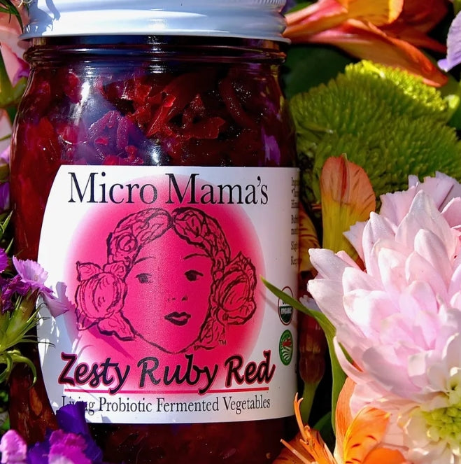 Jar of 'Micro Mama's Zesty Ruby Red' probiotic vegetables surrounded by flowers