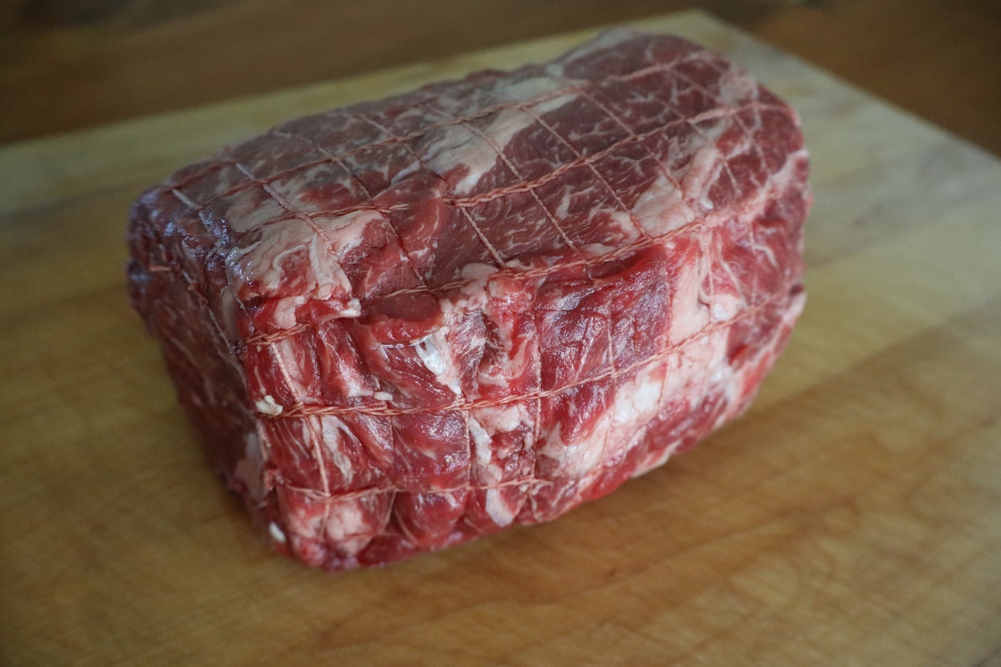 Raw chuck roast beef on a wooden cutting board