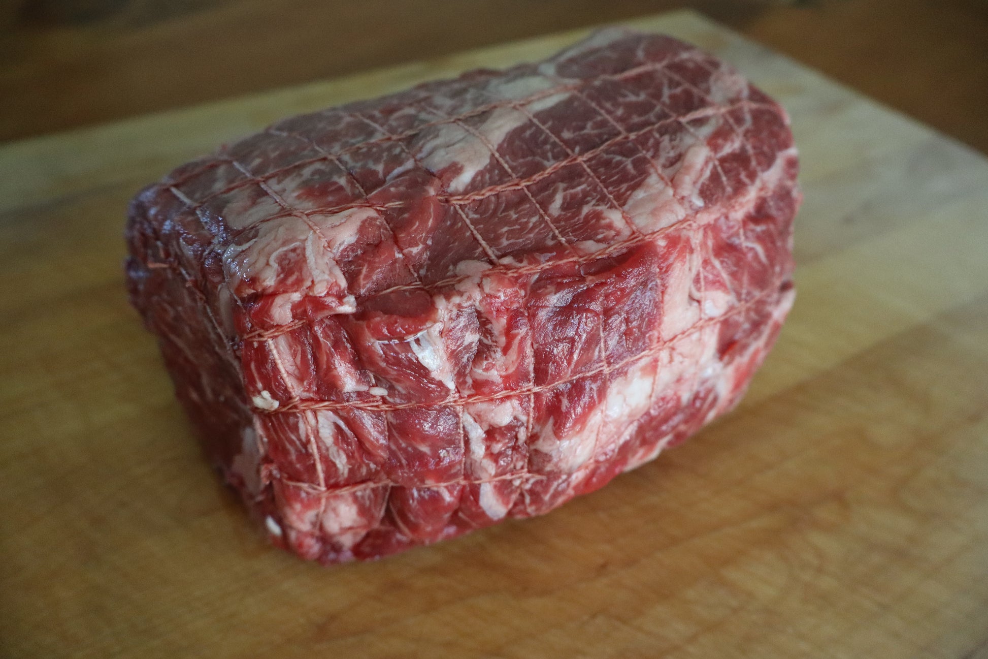 Raw chuck roast beef on a wooden cutting board