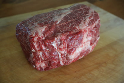 Raw chuck roast beef on a wooden cutting board