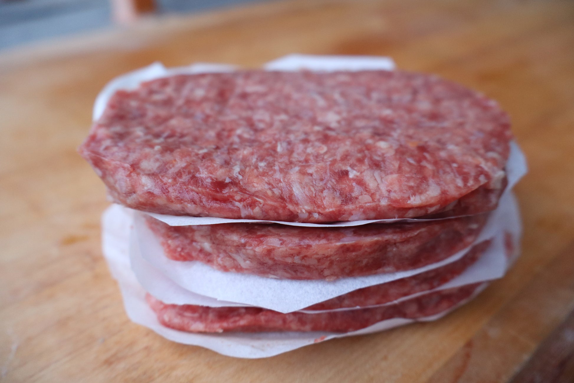Stack of raw hamburger patties on a wooden surface