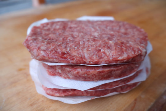 Stack of raw hamburger patties on a wooden surface