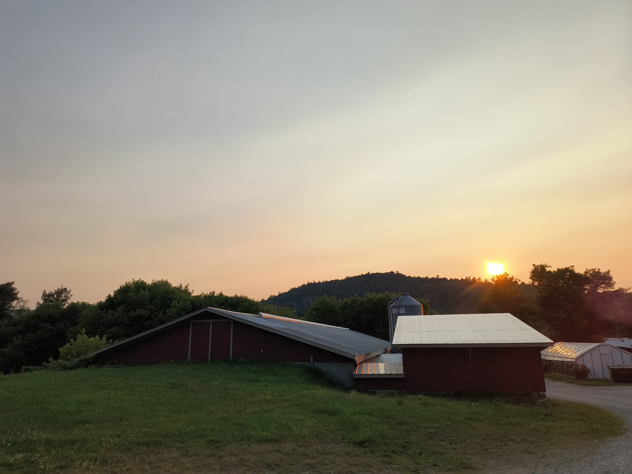 Sunset over a rural landscape with barns and trees at Robie Farm in New Hampshire